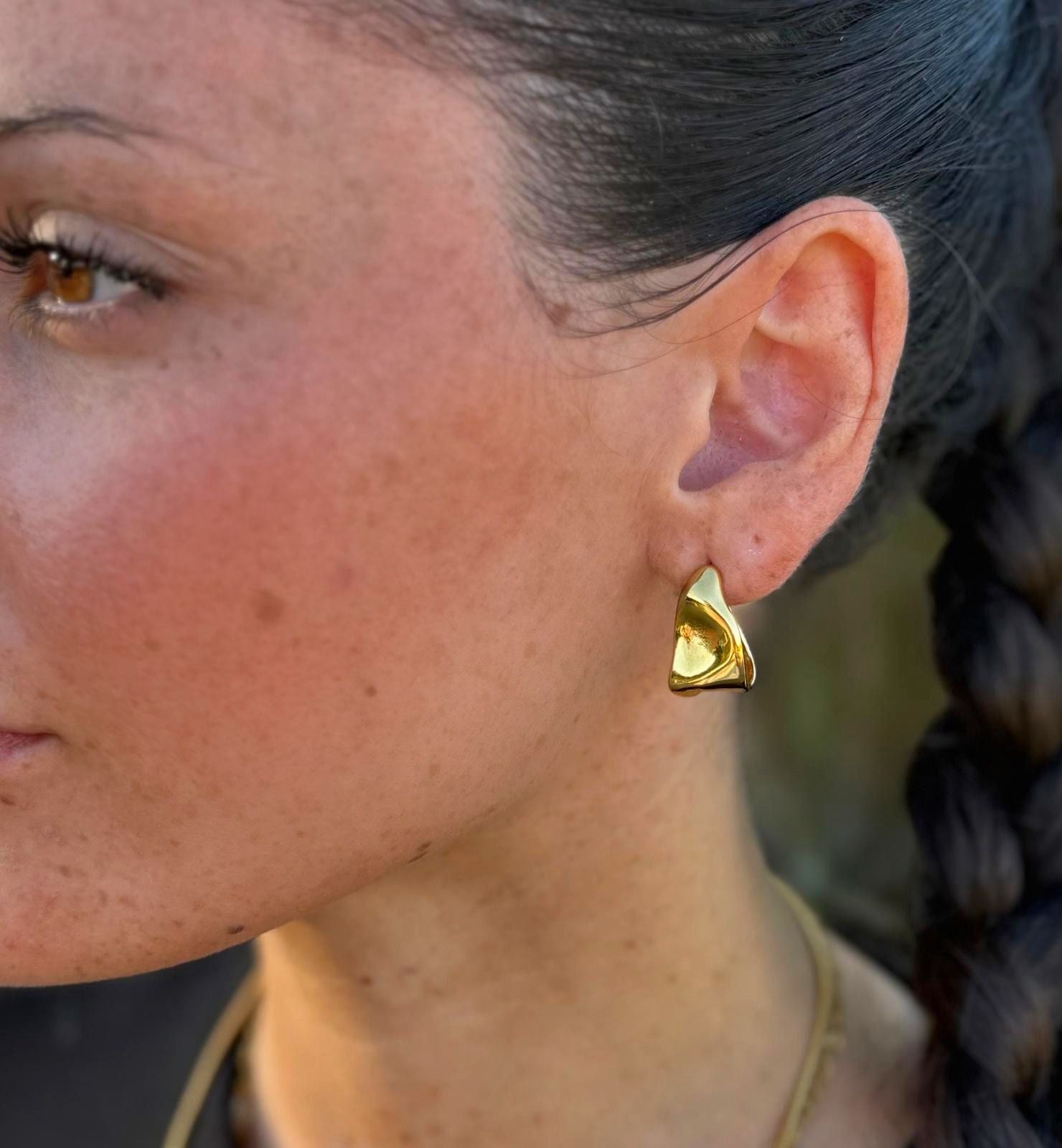 Calla Hoops goldene Creolen getragen – skulpturale Blütenblatt-Form