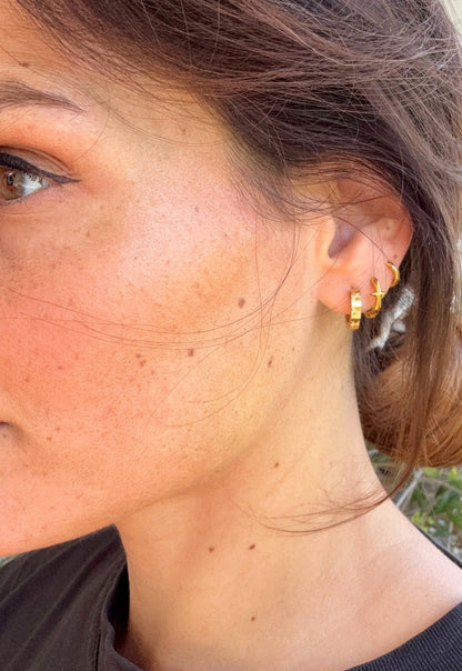 Nocta Star goldene Mini-Hoops mit Stern-Detail am Ohr getragen 